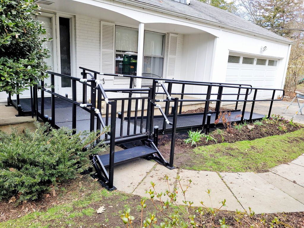 A black powder-coated ramp with a switchback at the front of a white ranch house