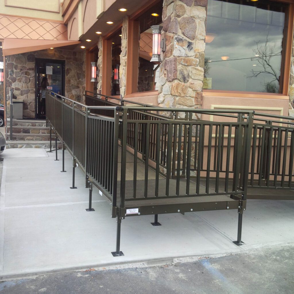 A dark powder-coated ramp running along the front of a stone-pillared retail entrance
