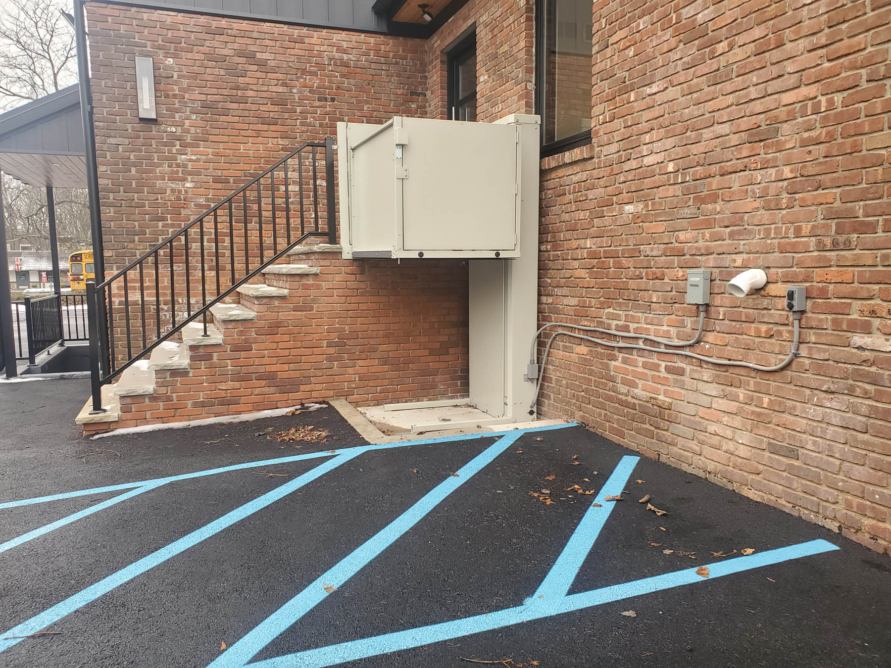 Vertical platform lift installed beside the steps at a building entrance